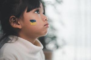 un bambino con la bandiera dell'ucraina sta piangendo. tristezza brama speranza. lacrime di bambini dalla guerra. evacuazione dei civili. libertà in Ucraina foto