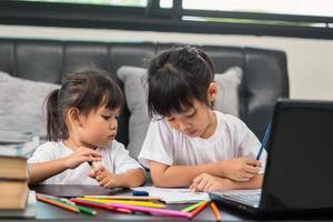 covid-19 coronavirus e apprendimento da casa, concetto di bambino a scuola a casa. i bambini piccoli studiano online imparando da casa con il laptop. foto