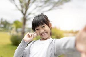 felice bambino asiatico si fa un selfie nel parco. foto