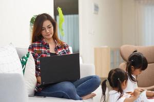 madre che lavora da casa con i bambini. quarantena e scuola chiusa durante l'epidemia di coronavirus. i bambini fanno rumore e disturbano la donna al lavoro. istruzione domiciliare e lavoro da freelance. foto