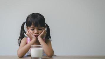 bicchiere di latte sul tavolo, con immagini sfocate di una ragazza sullo sfondo. non le piace foto