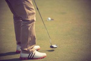 giocatore di golf al putting green che colpisce la palla in un colore hole.vintage foto