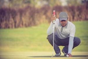 giocatore di golf professionista che mira al tiro con la mazza sul campo. golfista sul green in procinto di prendere il tiro foto