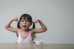 la bambina asiatica sta bevendo il latte da un bicchiere che era molto felice. foto