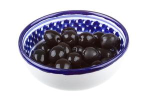 olive nere innaffiate con olio d'oliva in una ciotola isolata su uno sfondo bianco foto