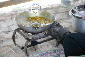 padella di ferro sul fornello portatile che cucina cibo indiano in viaggio, india. curry in padella bollente. foto