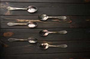 sei vecchi cucchiai d'argento su un fondo di legno rustico. foto