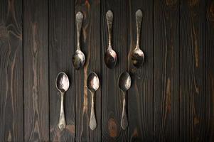 sei vecchi cucchiai d'argento su un fondo di legno rustico. foto