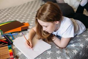 la ragazza dopo la scuola gioca a casa, disegna con matite e pennarelli foto