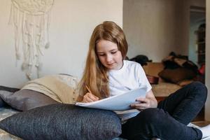 la ragazza dopo la scuola gioca a casa, disegna con matite e pennarelli foto