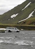 furgone fuoristrada che entra in un fiume glaciale in Islanda foto