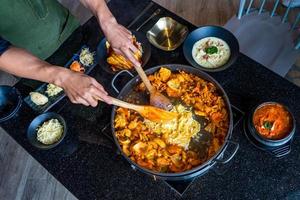 tokboki cibo tradizionale coreano torta di riso calda e speziata, combinazione e applicazione di sfoglia con formaggio e verdure sul tavolo nero foto