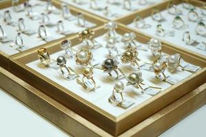 molti tipi di gioielli con anello di gemme si dispongono sul piatto d'oro nel negozio di gioielli con scatola a specchio. foto