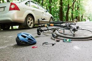 luogo di pericolo. bicicletta e incidente d'auto color argento sulla strada nella foresta durante il giorno foto