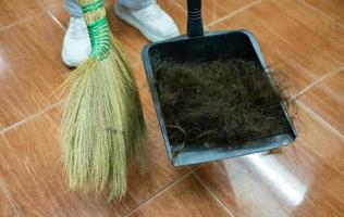 parrucchiere che usa una scopa per spazzare i capelli dei clienti in una paletta dopo aver tagliato i capelli. foto