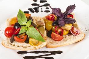 pomodori succosi su pane fresco, pesto come guarnizione foto