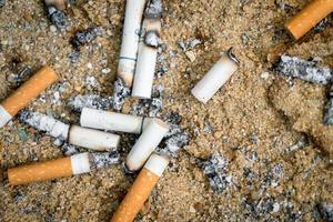 le sigarette usate vengono gettate nella sabbia nel cestino della cenere delle sigarette. foto