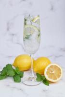 fresco cocktail estivo con limoni, menta e ghiaccio, immagine di messa a fuoco selettiva, mojito in una tazza di vetro, limonata fresca di agrumi con lime e limoni. bevanda fresca e fresca per il concetto estivo. foto