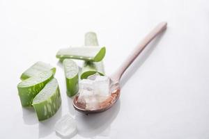 gel di aloe vera su cucchiaio di legno con aloe vera su sfondo bianco, l'aloe vera è piante verdi tropicali. cosmetici a fette di rinnovo biologico naturale di aloe vera, medicina alternativa. concetto di cura della pelle biologica. foto