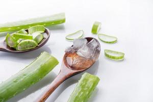 gel di aloe vera su cucchiaio di legno con aloe vera su sfondo bianco, l'aloe vera è piante verdi tropicali. cosmetici a fette di rinnovo biologico naturale di aloe vera, medicina alternativa. concetto di cura della pelle biologica. foto