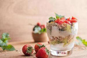 muesli fatto in casa, ciotola di muesli d'avena con yogurt, mirtilli freschi, gelso, fragole, kiwi, menta e noci per una sana colazione, copia spazio. concetto di colazione sana. mangiare pulito. foto