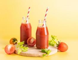 bottiglia di vetro di succo di pomodoro, lime con mazzo di pomodori freschi e luminosi isolati su sfondo verde, prezzemolo verde. bevanda vegetale. foto