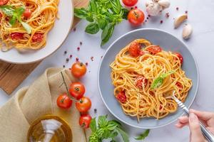 gustosi spaghetti italiani classici appetitosi con salsa di pomodoro, parmigiano e basilico sul piatto e ingredienti per cucinare la pasta sul tavolo di marmo bianco. spazio di copia vista dall'alto piatto. foto