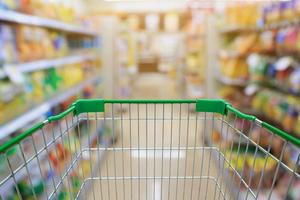 carrello della spesa nel corridoio del supermercato e scaffali con sfondo sfocato foto