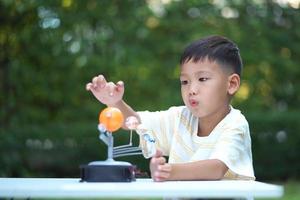 ragazzo asiatico che vive giocattoli del sistema solare, attrezzature per l'apprendimento domestico, durante il nuovo cambiamento normale dopo la situazione pandemica dell'epidemia di coronavirus o post covid-19 foto