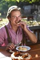 uomo attraente mangia formaggio tradizionale con pretzel in una baviera
