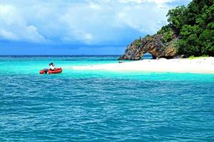 turista che prende una barca rossa per l'isola sul mare delle andamane, krabi, tailandia. bellissimo mare profondo e sabbia bianca con nuvole di cielo blu in estate foto