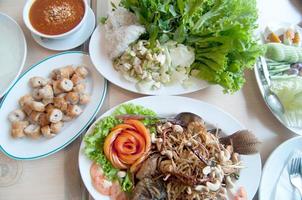 cibo tailandese nel tavolo da pranzo - pesce cotto, salsa di peperoncino foto