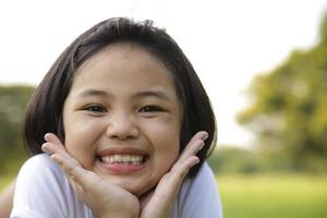 la bambina asiatica si rilassa e sorride felicemente nel parco foto