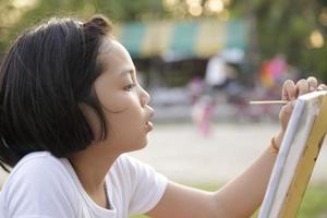 bambina asiatica che dipinge nel parco foto