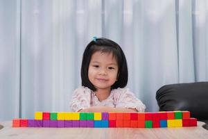 immagine ritratto di 4-5 anni. bambino asiatico seduto sorriso, con blocco di legno colorato posto sul tavolo. scuola domestica al coperto. in classe. il bambino carino ama imparare attraverso il gioco. spazio vuoto per inserire il testo foto