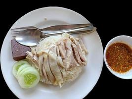 riso al pollo hainanese mangiare con salsa su sfondo nero. foto