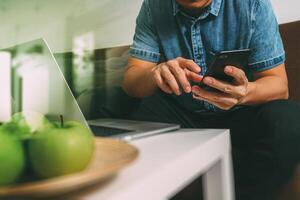 mano hipster utilizzando computer portatile e pagamenti mobili online business, canale omni, seduto sul divano in soggiorno, mele verdi nel vassoio di legno, filtro foto