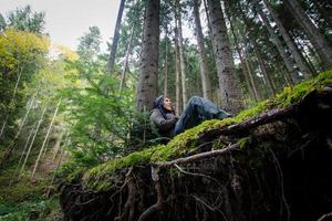 escursionista femminile con zaino che cammina sulle strade di montagna, sfondo foresta autunnale foto