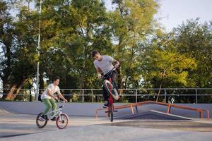 gruppo di giovani con biciclette bmx in skate plaza, ciclisti acrobatici nello skatepark foto