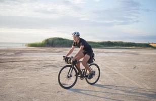 il turista in bicicletta con zaini e casco viaggia nel deserto sulla sua bicicletta da ciclocross durante il tramonto foto