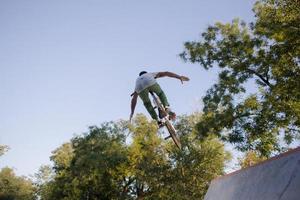 bmx rider che si allena e fa acrobazie in street plaza, bicyxle stunt rider in cocncrete skatepark foto