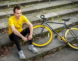 un giovane si è fermato a riposare con la sua bicicletta in un parco pubblico. foto