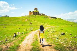 donna turistica femminile a piedi verso le rovine della cattedrale di bana, famoso monumento storico ortodosso georgiano in turchia foto