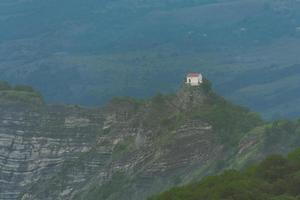 cappella bianca sulla cima della collina nella campagna della georgia dal caucaso tbilisi all'autostrada dei monti didgori foto