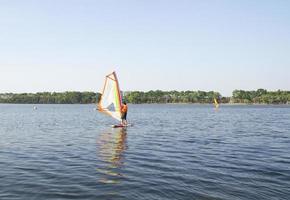 uomo che fa windsurf sul lago calmo foto