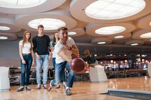 palla quasi volante. i giovani amici allegri si divertono al bowling club durante i fine settimana foto