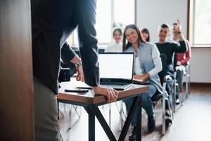 l'uomo ha una domanda. mano alzata. gruppo di persone alla conferenza di lavoro nella moderna classe durante il giorno foto