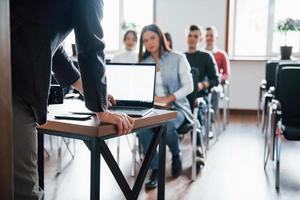 usando il portatile. gruppo di persone alla conferenza di lavoro nella moderna classe durante il giorno foto