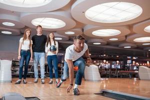 voglio colpire. i giovani amici allegri si divertono al bowling club durante i fine settimana foto