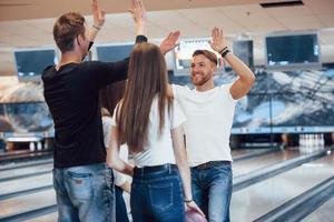 tutti sono soddisfatti. i giovani amici allegri si divertono al bowling club durante i fine settimana foto